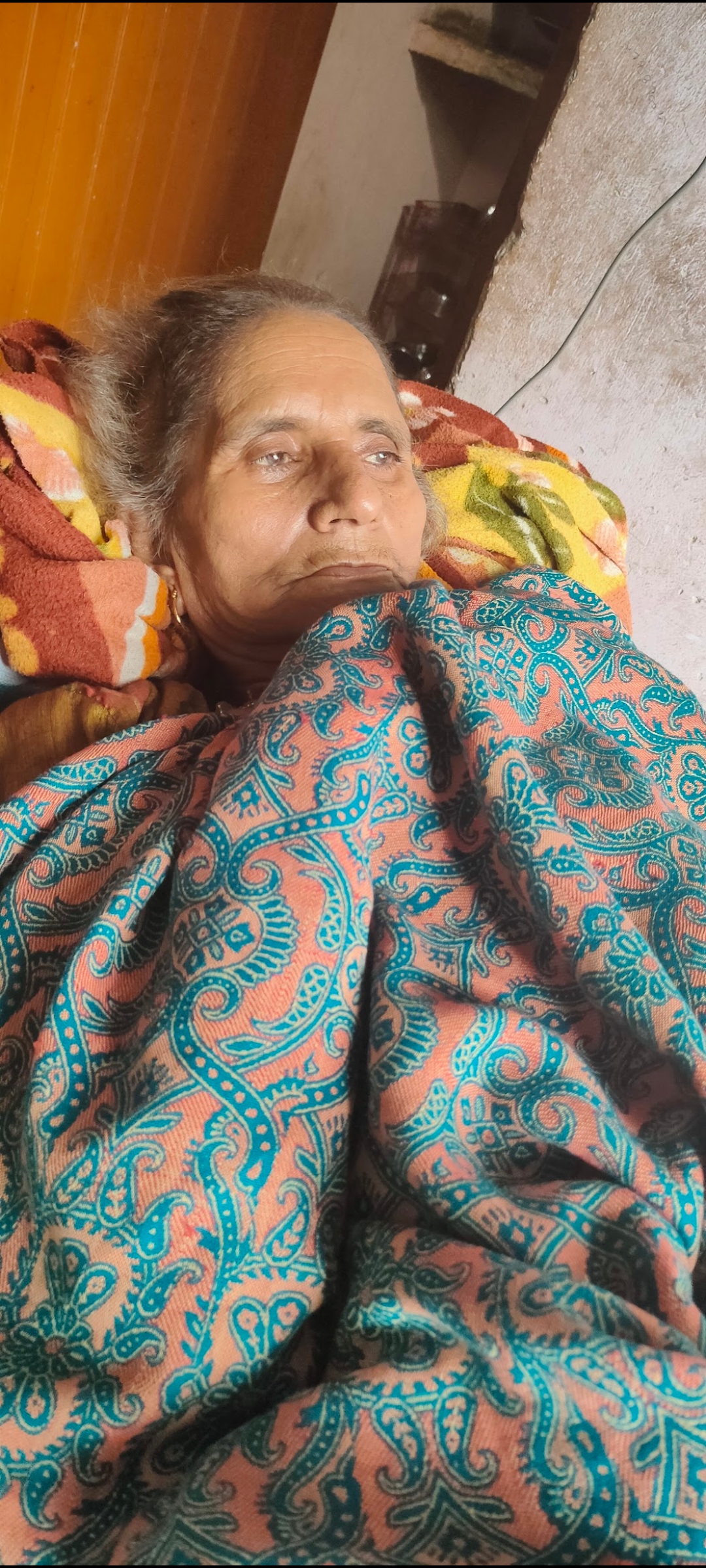 Dadi resting under paisley blanket, gaze averted
